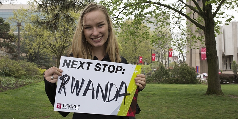 Maggie Andresen holding a sign that says "Next stop: Rwanda".