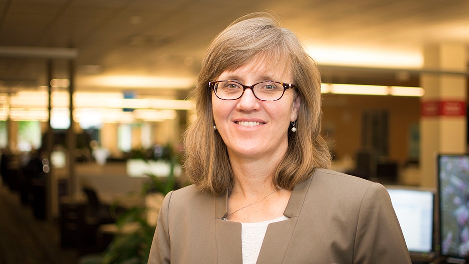 A woman wearing glasses and a brown blazer.