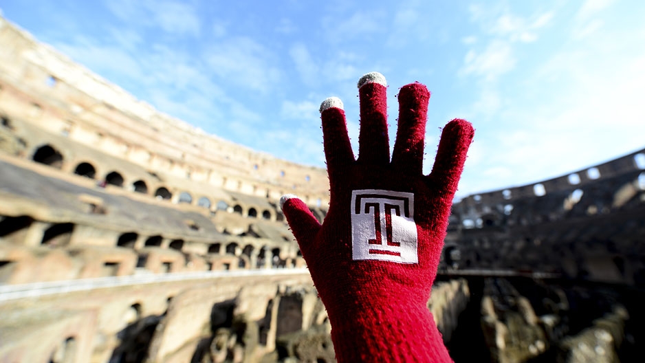  A hand wearing a Temple glove in front of the Colosseum in Rome.