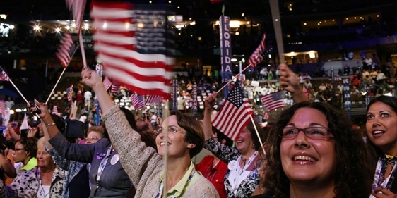 Attendees waving American flags in the crowd of the Democratic National Convention.