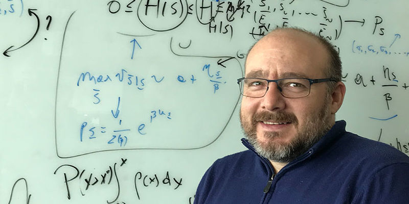 Associate Professor of Biology Vincenzo Carnevale in front of white board with equations