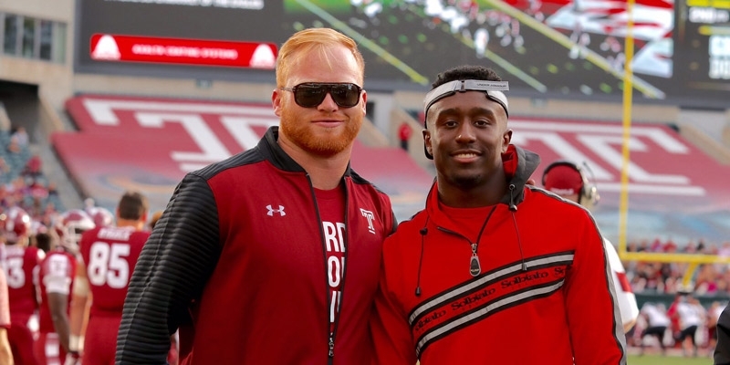 Two men standing on the sideline of a Temple football game. 