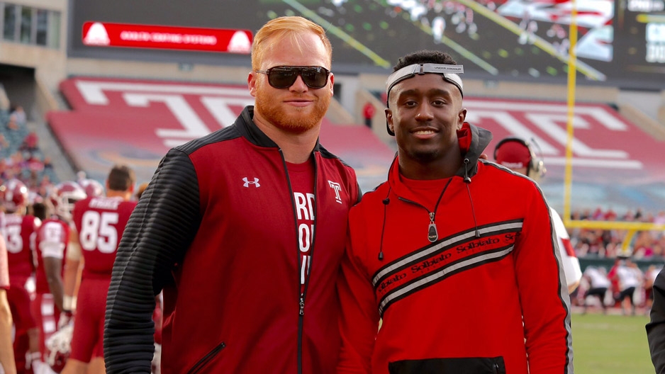 Two men standing on the sideline of a Temple football game. 