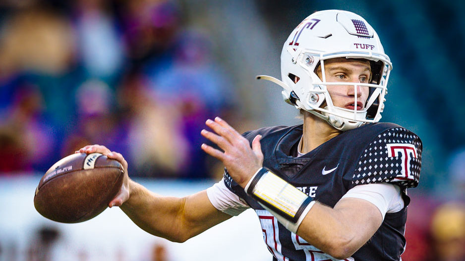 Image of a college athlete wearing a white helmet with a Temple logo and a black, cherry and white jersey, throwing a football.