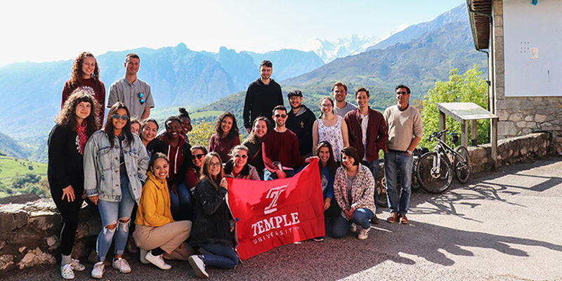  Mountains in the background, a group of Temple students holding a Temple cherry flag.