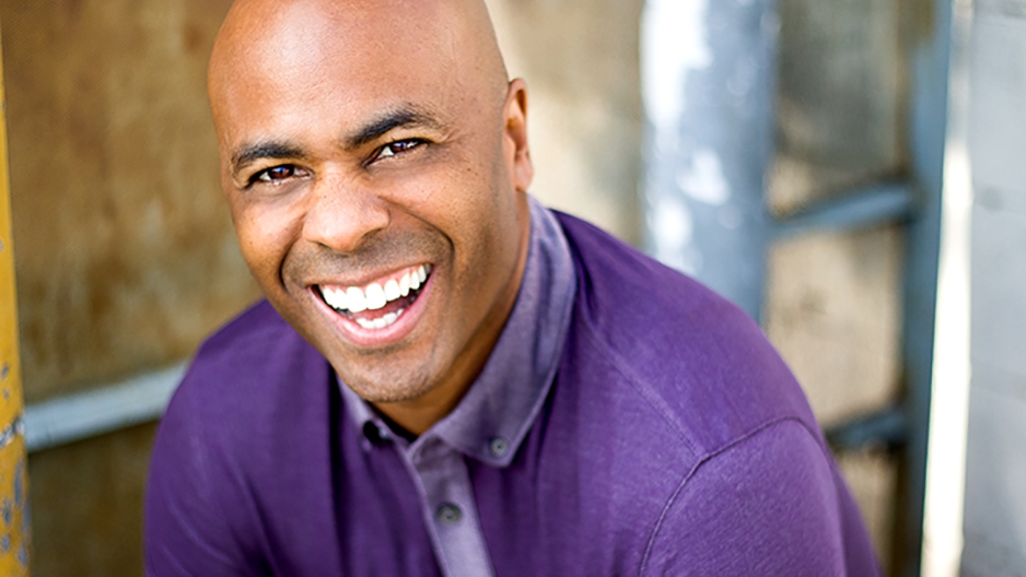 Fred Thomas Jr. wearing a purple shirt and smiling