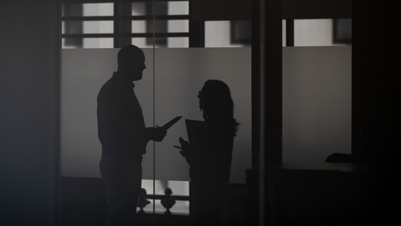 Two profiled silhouettes of two staff members talking with each other.