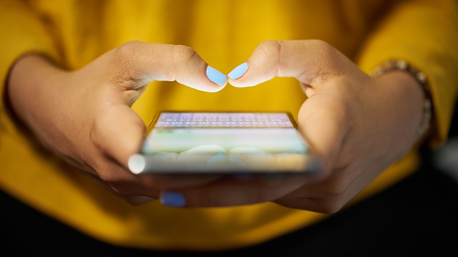 Hands typing on a cell phone.  