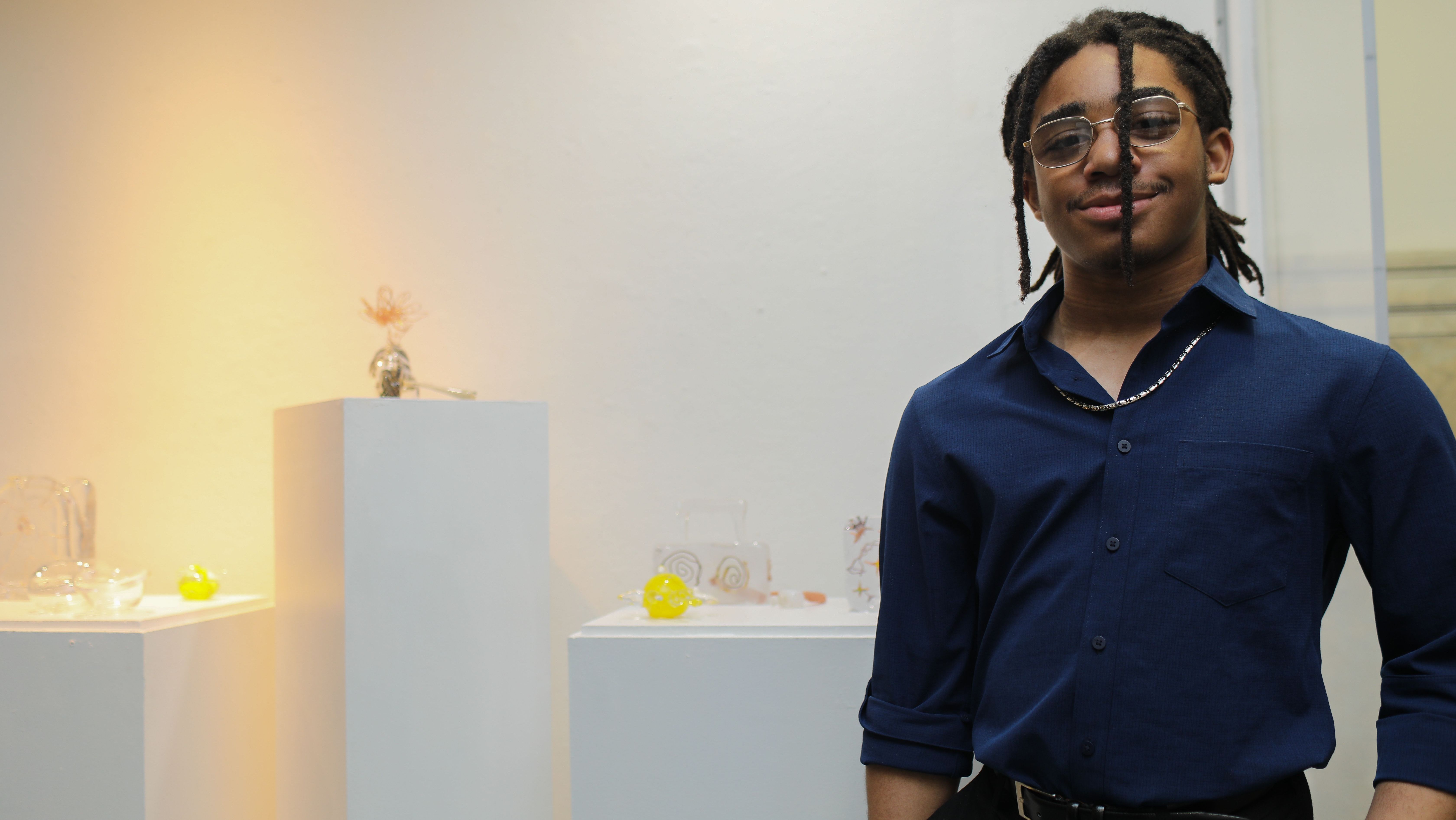 Creative Scholars student stands next to artwork