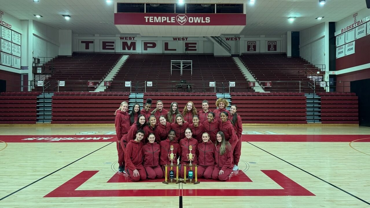  Image of Temple’s dance team wearing cherry and white posing in front of trophies.  