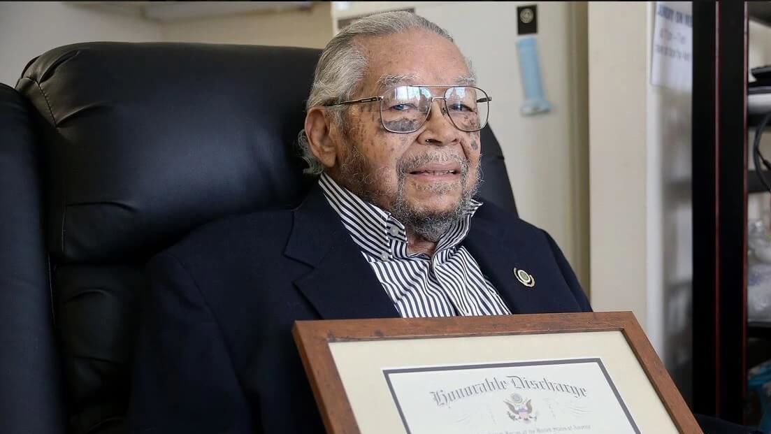 Nelson Henry Jr. holding his honorable discharge certificate.