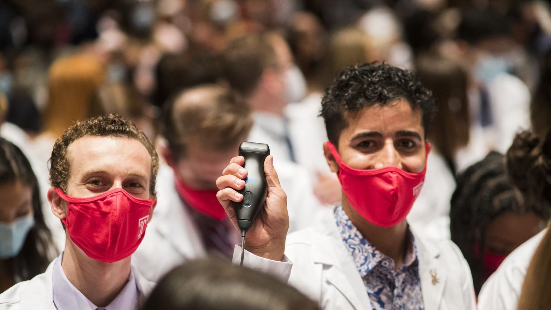 A student displays their new ultrasound device at a white coat ceremony.