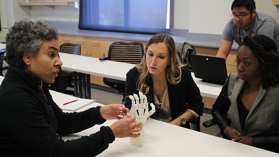 Students working with a prosthetic hand in a classroom.