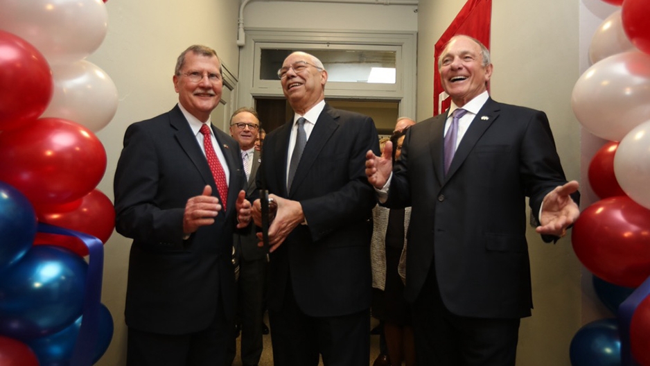 Three men smiling as they cut the ribbon at the veteran center.