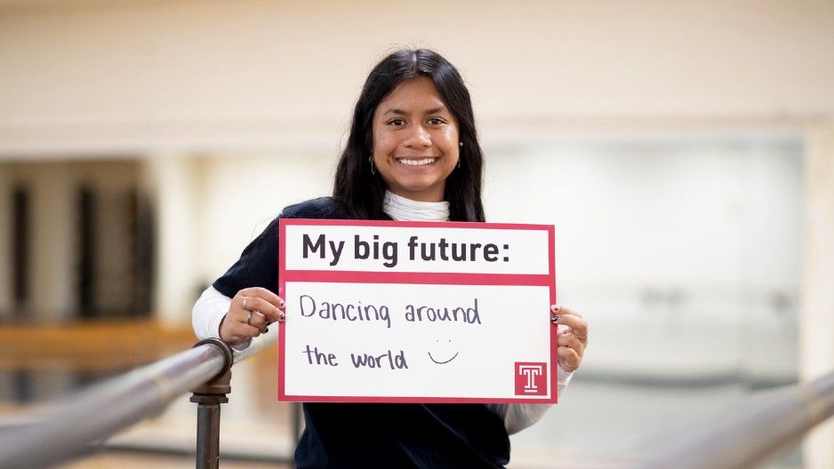 Smith holds a sign reading "My big future: Dancing around the world :)" in a dance studio