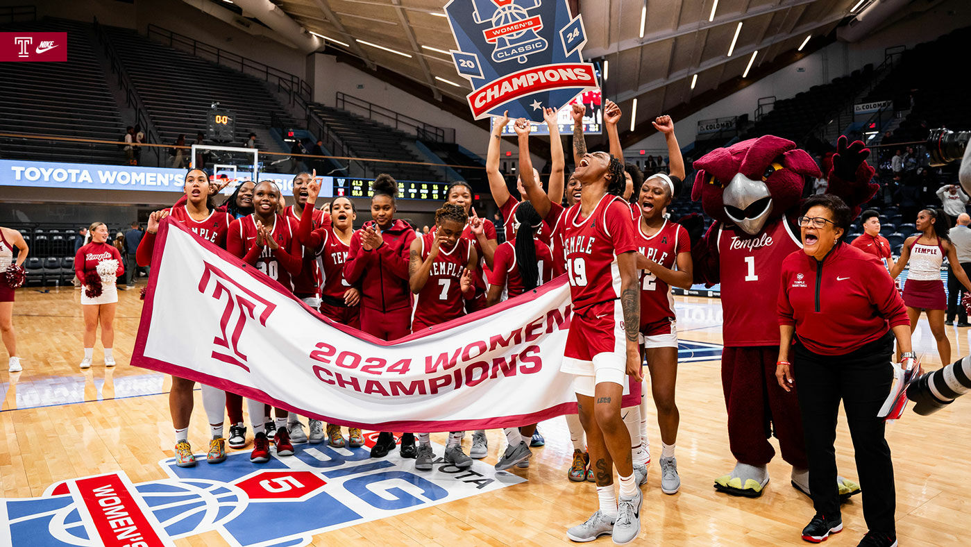 Image of Temple women’s basketball in the cherry and white celebrating on the court. 