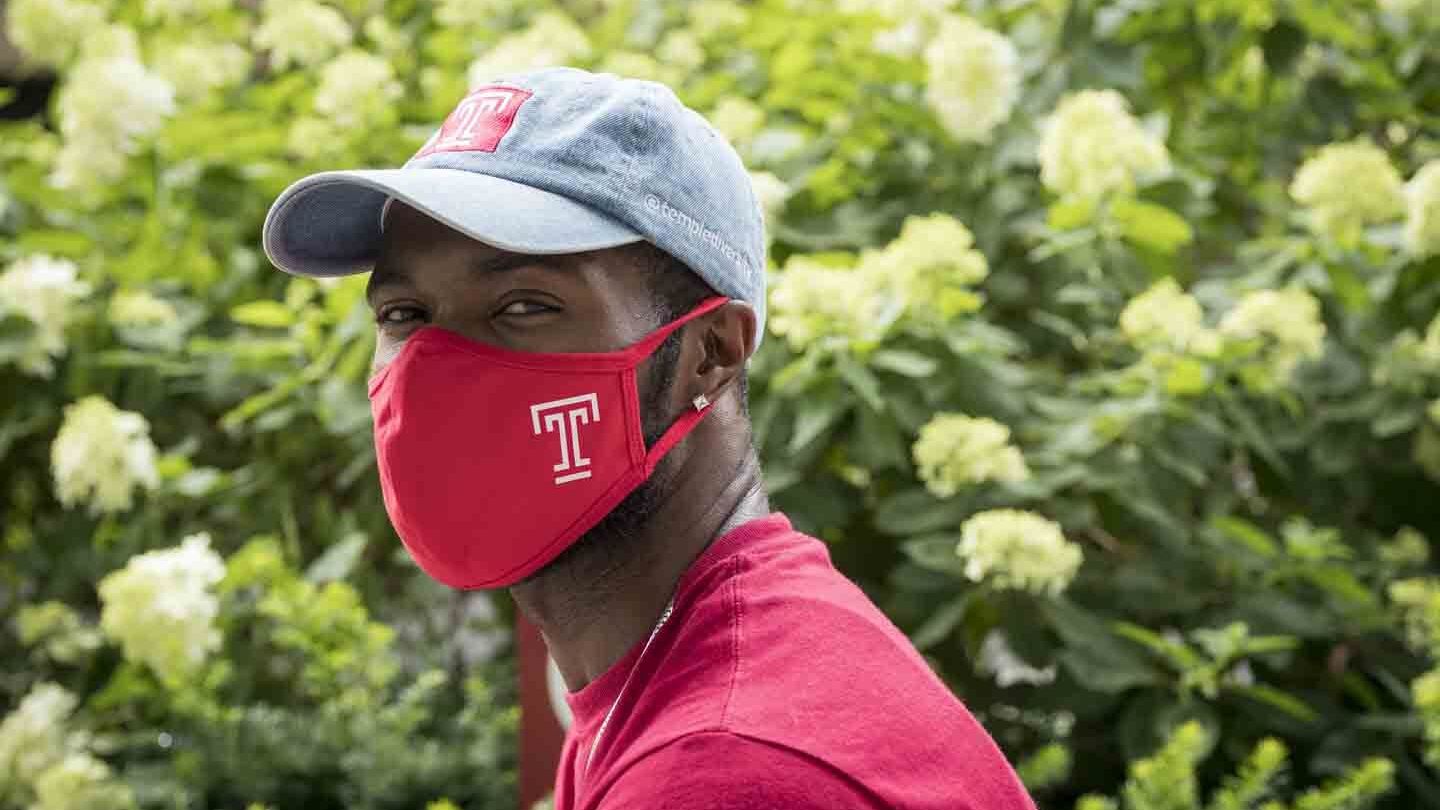 A Temple community member wearing a Temple-branded mask. 