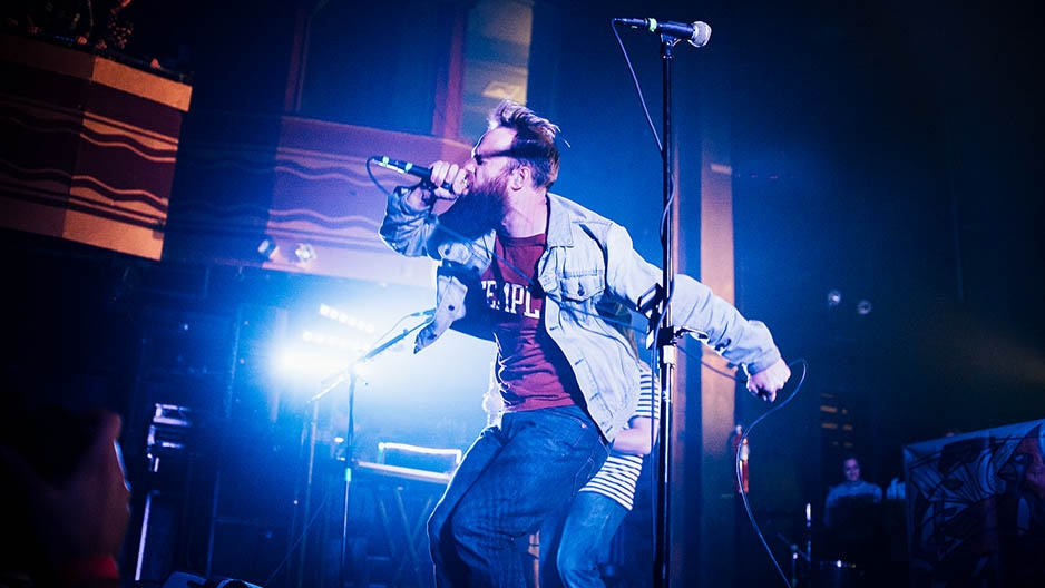 Dan Campbell performing on stage while wearing a Temple t-shirt.