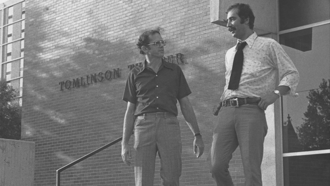 Image of two people walking down the steps of Tomlinson Theater. 