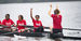 Image of children with smiles wearing red t-shirts, rowing a boat.  