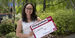 Trista Mayo standing outside holding up a Temple Made for sign