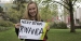 Maggie Andresen holding a sign that says "Next stop: Rwanda".