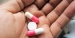 A hand holding three pills.