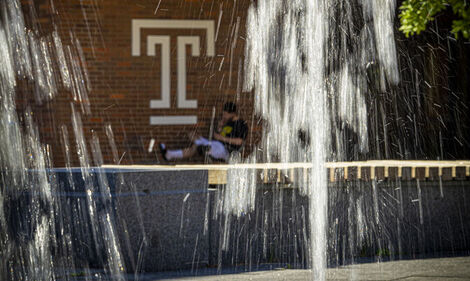 A student is pictured behind a fountain.