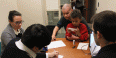 a man looking over forms with attorneys as his young son sits on his lap.