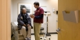 A doctor interacting with a patient inside an exam room.