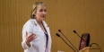 Darilyn Moyer wearing a lab coat and speaking at a podium.