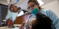 A female patient looking in a handheld mirror at her new dental crown.