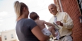  A man holding a notebook interviewing a woman holding a baby.