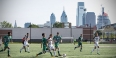 Temple men’s soccer team playing at the new sports complex with the Philadelphia skyline in the background.