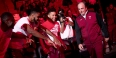 Basketball players welcoming their coach to the court.