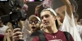 A student taking video of himself at a basketball game. 