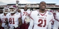 Temple football players smiling and celebrating on the field after a big win.