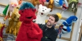 Michael Latini holding a furry red puppet.