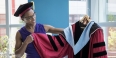 Musu Davis holding and eyeing the cherry graduation gown