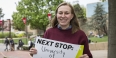 Hope Watson holding a sign that says "Next stop: University of Cambridge".