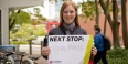Amelia Schunder holding up a sign that says Next Stop: Lyon, France