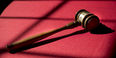  Image of a gavel placed on a table with red cloth.  