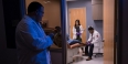 A physician watching two students work with a patient in a clinic room