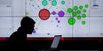 man on a laptop in silhouette with data visualization on screen