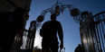 A student in silhouette walks through gates on Temple's Main Campus.