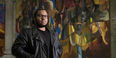 yler A. Ray stands in front of one of 14 murals inside the Church of the Advocate.