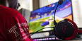 Image of a student wearing a Temple esports jersey playing a PC game.    