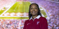 A woman wearing a cherry and white Temple shirt pictured with the background of Lincoln Financial Field.  