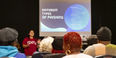 Image of a student wearing a cherry and white sweater speaking to the community. 