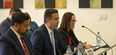 Individuals sitting at a table in front of small microphones